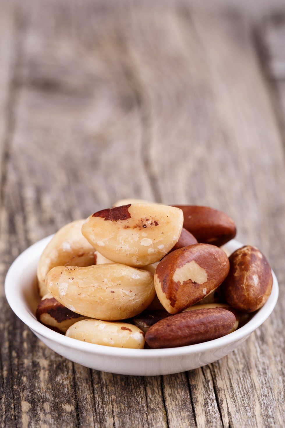 Brazil nuts on a spoon on wooden background.