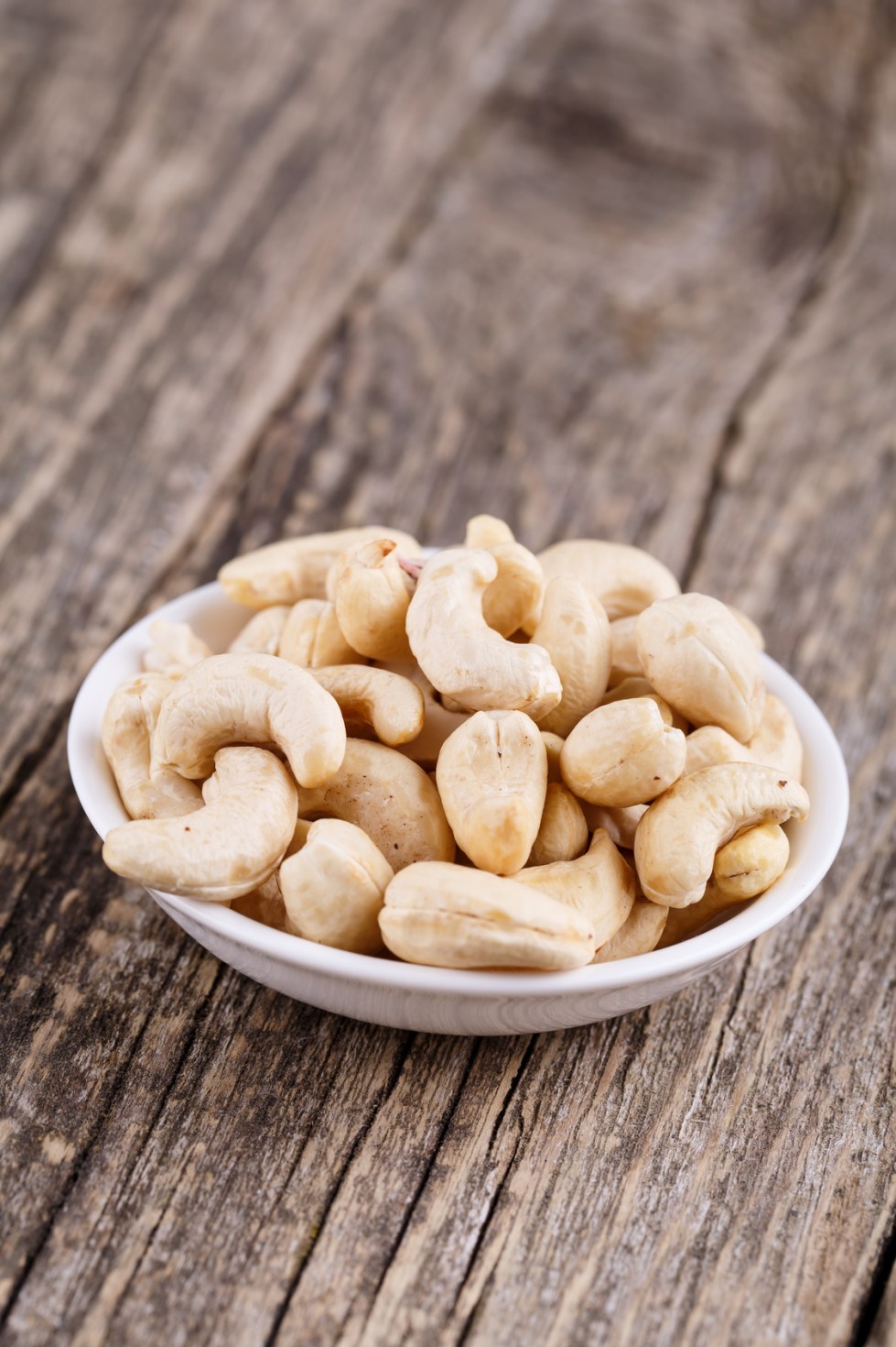 Cashew nuts on a plate on wooden background.