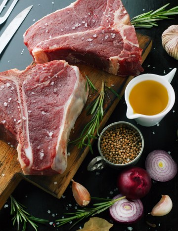 Raw meat t-bone steak with herbs, spices, garlic and rosemary