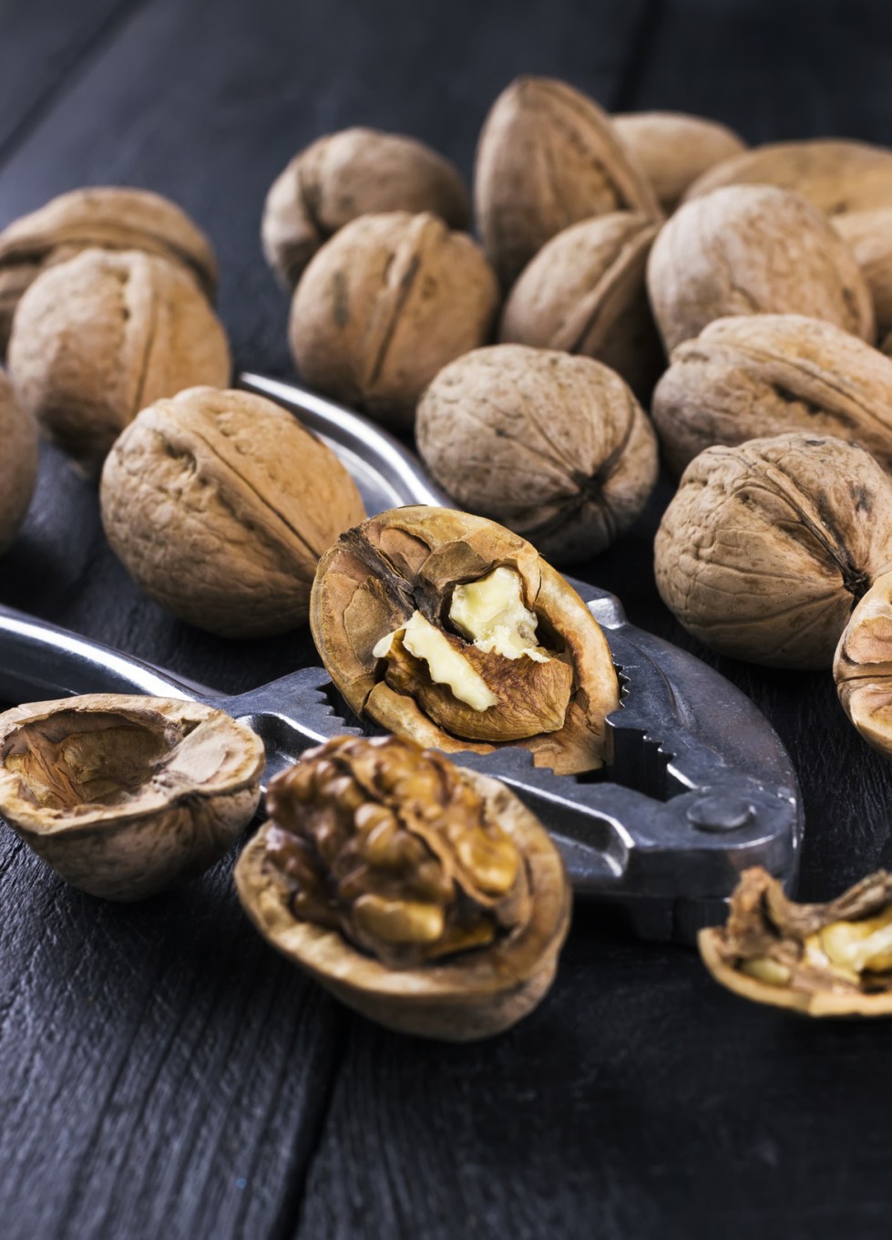 Walnut kernels and whole walnuts on wooden background